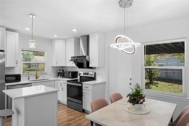 kitchen featuring electric range, a center island, wall chimney range hood, black microwave, and a sink