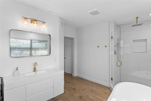 bathroom with a stall shower, baseboards, wood finished floors, a freestanding bath, and vanity