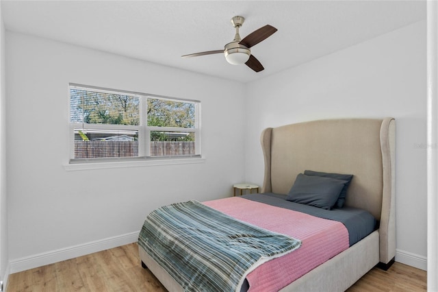 bedroom featuring ceiling fan, baseboards, and wood finished floors