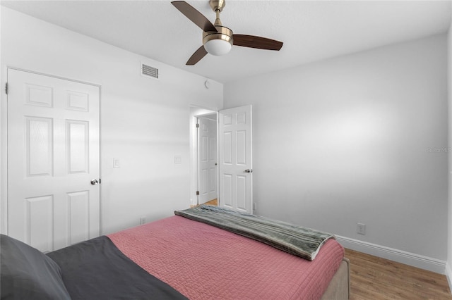 bedroom with light wood-style floors, visible vents, ceiling fan, and baseboards