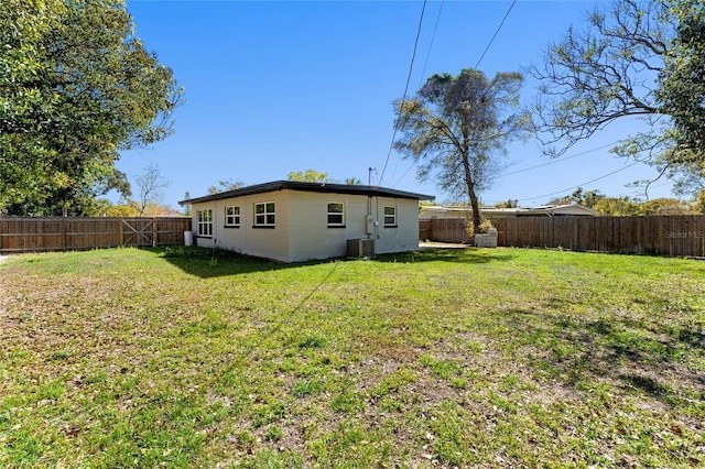 rear view of house with a fenced backyard, central AC, and a lawn