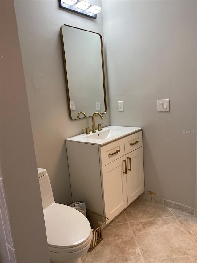 half bath with baseboards, vanity, and toilet