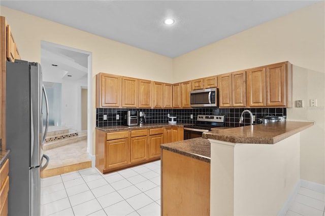 kitchen with light tile patterned floors, stainless steel appliances, dark countertops, backsplash, and a peninsula