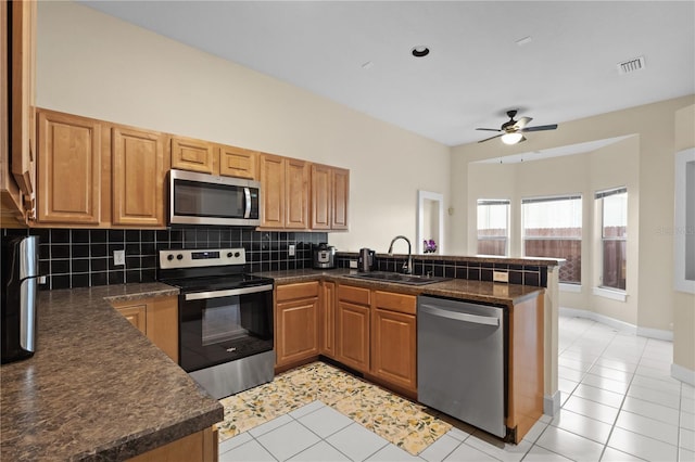 kitchen with stainless steel appliances, dark countertops, visible vents, a sink, and a peninsula