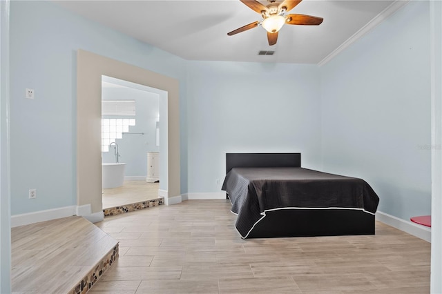 bedroom featuring wood finished floors, a ceiling fan, visible vents, baseboards, and ensuite bath