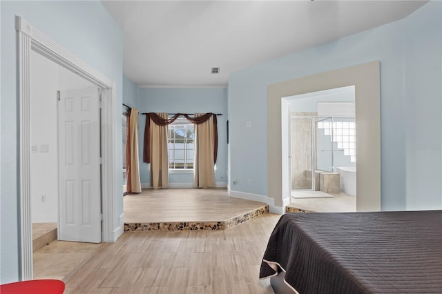 bedroom featuring ensuite bathroom, multiple windows, wood finished floors, and baseboards