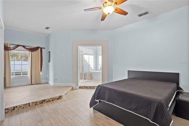 bedroom with ensuite bathroom, wood finished floors, visible vents, and baseboards