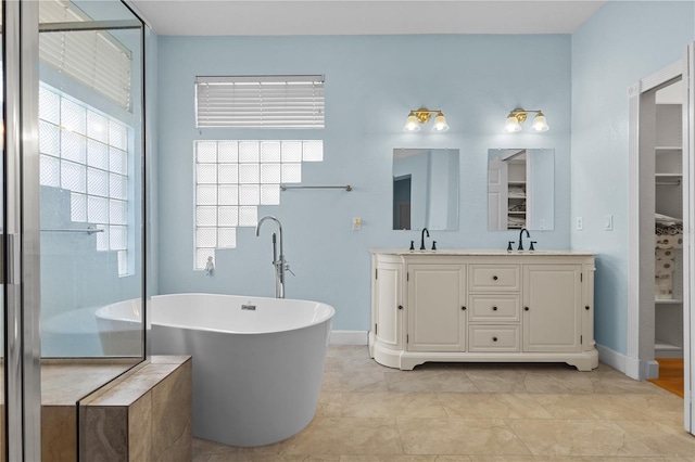 full bathroom featuring baseboards, a sink, a freestanding bath, and double vanity