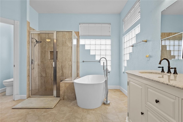 bathroom featuring a freestanding bath, toilet, a shower stall, vanity, and baseboards