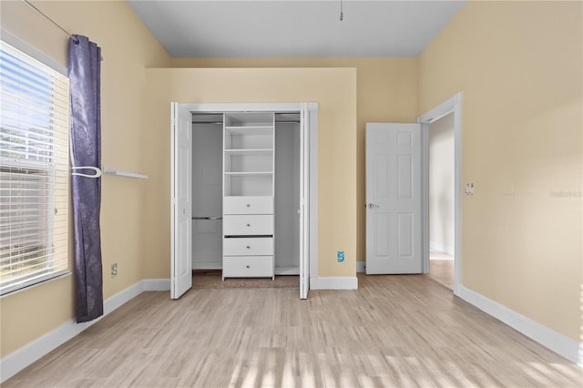 unfurnished bedroom with a closet, light wood-style flooring, and baseboards