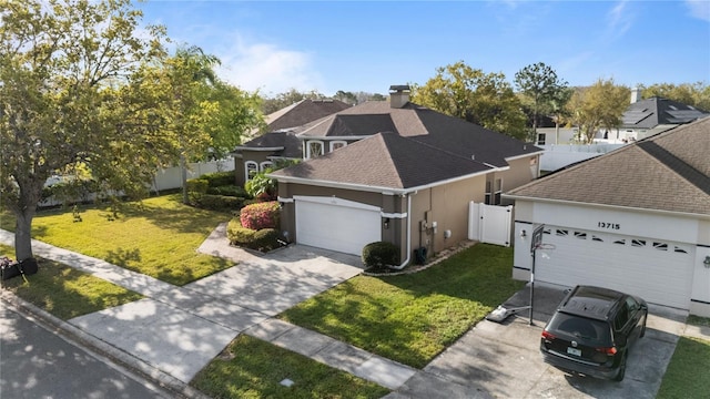 view of front of house with concrete driveway, an attached garage, a gate, fence, and a front lawn