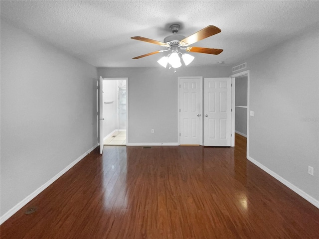 unfurnished bedroom featuring a textured ceiling, dark wood finished floors, visible vents, and baseboards