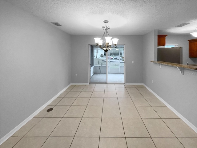 unfurnished dining area with a chandelier, light tile patterned floors, visible vents, and baseboards