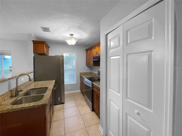 kitchen featuring brown cabinets, light tile patterned floors, stainless steel appliances, visible vents, and a sink