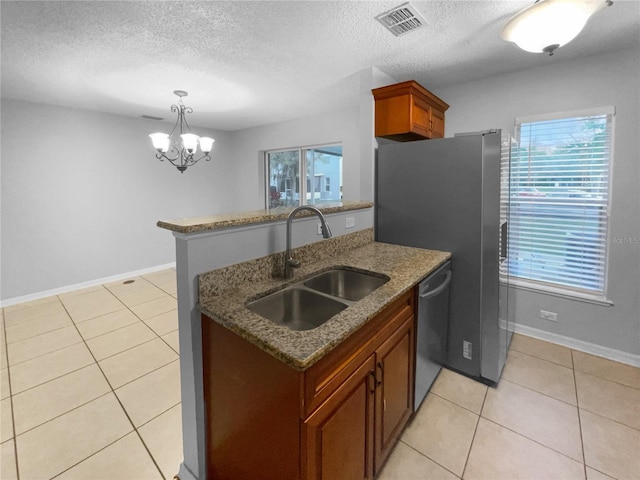 kitchen featuring a peninsula, a sink, visible vents, stainless steel dishwasher, and dark stone countertops