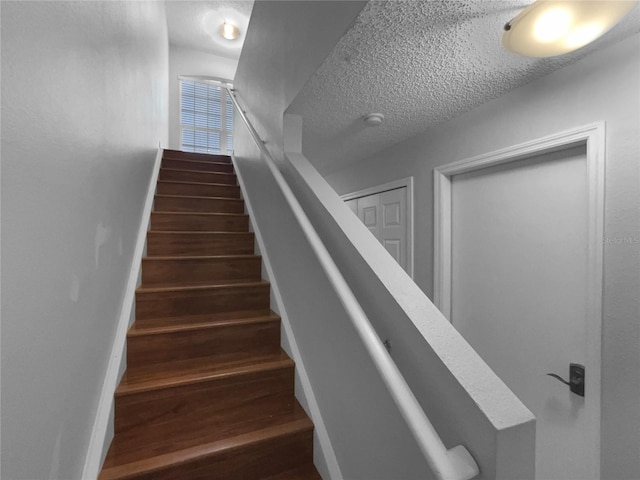 stairway with baseboards, a textured ceiling, and wood finished floors