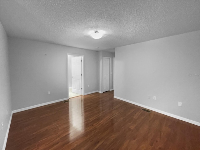 unfurnished room featuring visible vents, a textured ceiling, baseboards, and wood finished floors