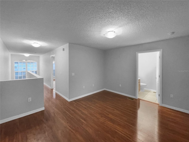 unfurnished room featuring baseboards, visible vents, and wood finished floors