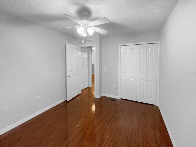 unfurnished bedroom with baseboards, ceiling fan, wood finished floors, a textured ceiling, and a closet