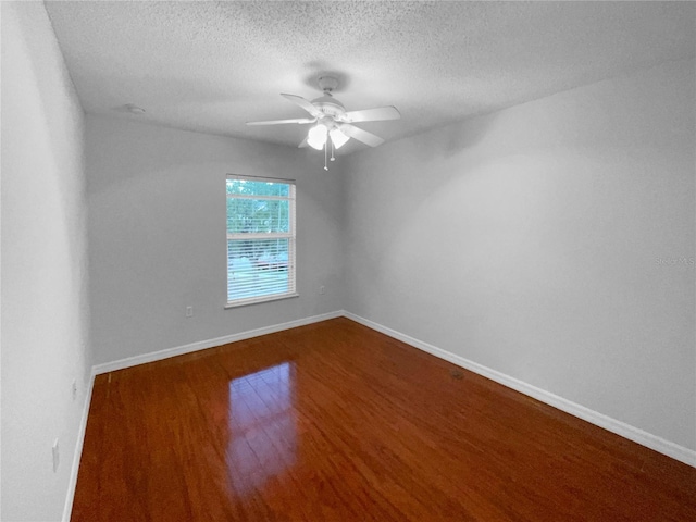 empty room featuring ceiling fan, a textured ceiling, baseboards, and wood finished floors