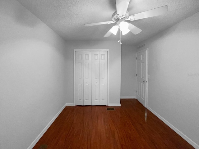 unfurnished bedroom featuring visible vents, baseboards, wood finished floors, a textured ceiling, and a closet