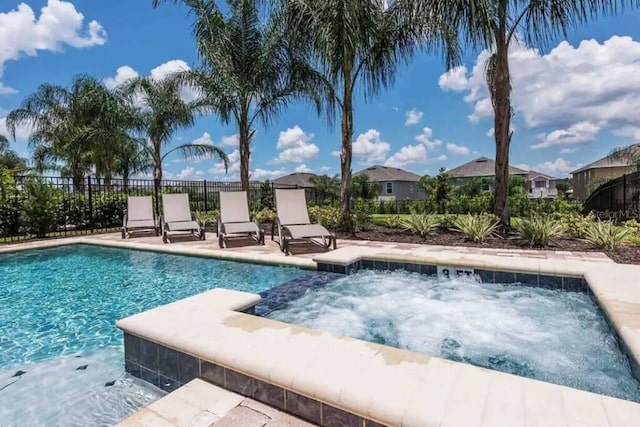 view of swimming pool featuring an in ground hot tub, fence, a fenced in pool, and a patio area