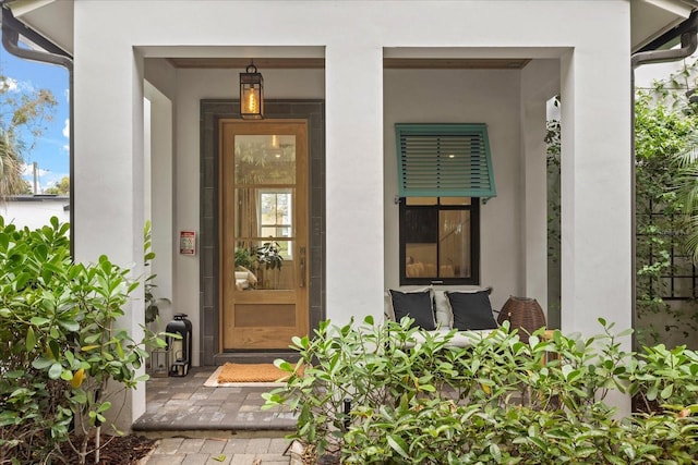 view of exterior entry with a porch and stucco siding