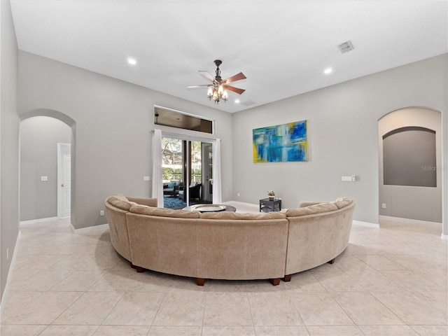 living room featuring light tile patterned floors, visible vents, arched walkways, and a ceiling fan