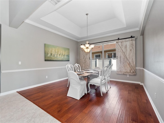 dining room with an inviting chandelier, a tray ceiling, wood finished floors, and baseboards