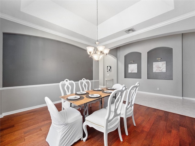 dining space featuring visible vents, baseboards, a raised ceiling, and wood finished floors