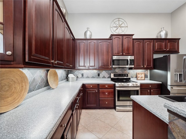 kitchen featuring light tile patterned flooring, decorative backsplash, appliances with stainless steel finishes, and light countertops