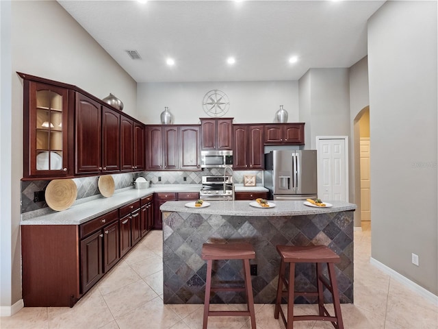 kitchen with visible vents, backsplash, a center island, arched walkways, and appliances with stainless steel finishes