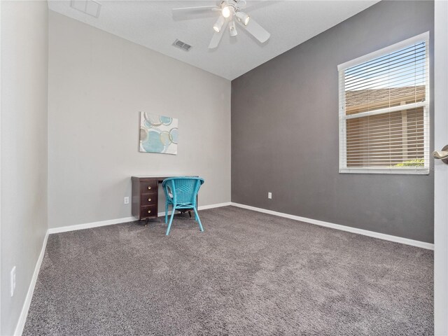 unfurnished office featuring visible vents, baseboards, vaulted ceiling, carpet floors, and a ceiling fan