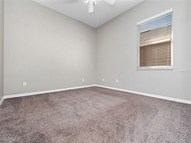 carpeted spare room featuring baseboards and a ceiling fan