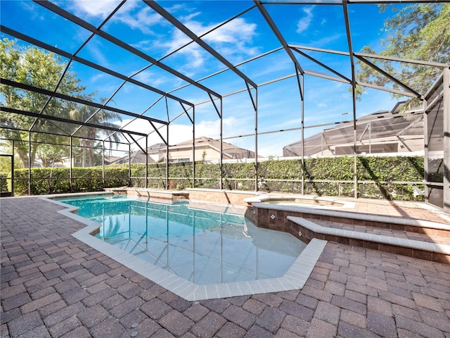 pool with glass enclosure, a patio, and an in ground hot tub