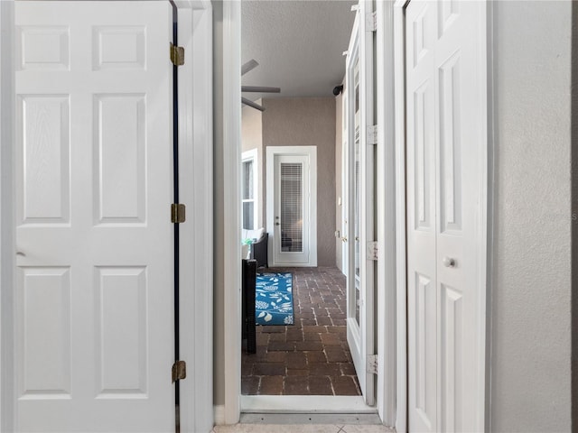 hall featuring brick floor and a textured ceiling