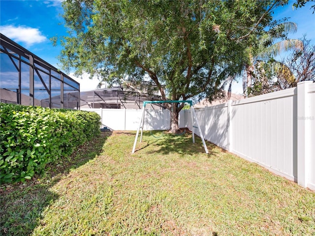 view of yard with a lanai, a fenced backyard, and a playground