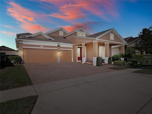 view of front of house with decorative driveway, a garage, and stucco siding