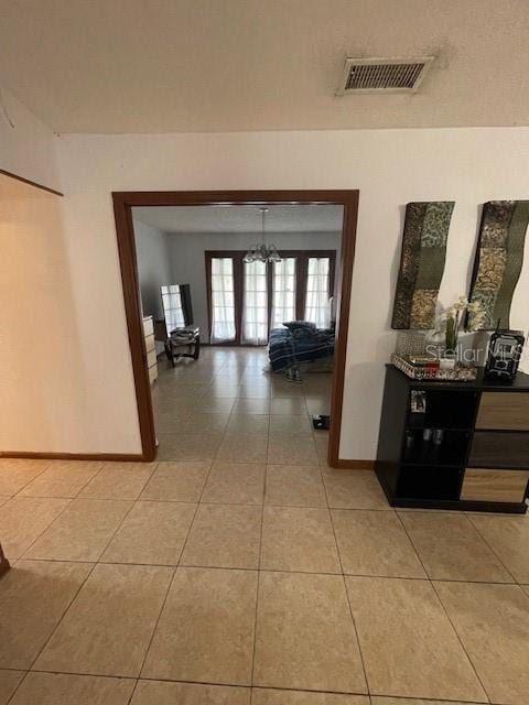 hall featuring light tile patterned floors, visible vents, and baseboards