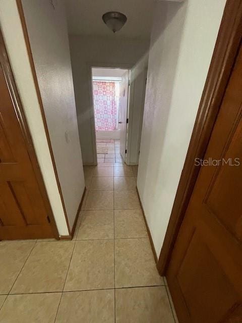 hall featuring light tile patterned flooring and baseboards