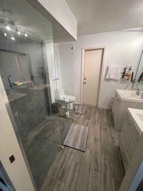 bathroom featuring washer / dryer, toilet, wood tiled floor, vanity, and a shower stall