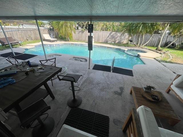 view of pool featuring a fenced backyard, a pool with connected hot tub, and a patio