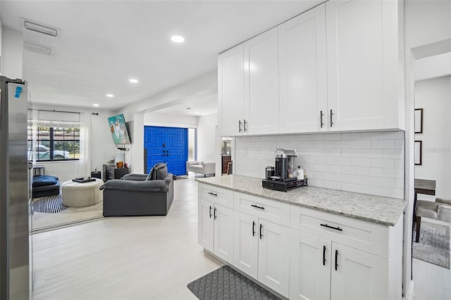 kitchen featuring white cabinets, tasteful backsplash, open floor plan, and freestanding refrigerator