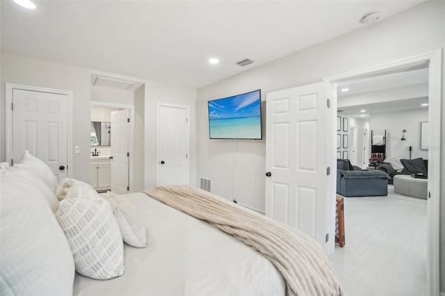 bedroom featuring attic access, visible vents, ensuite bathroom, a sink, and recessed lighting