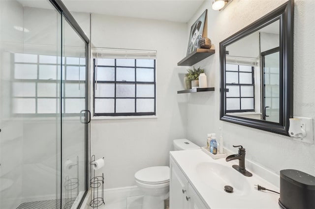 bathroom featuring vanity, a shower stall, toilet, and baseboards