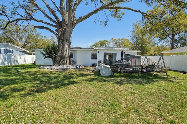 back of house with a fenced backyard and a yard