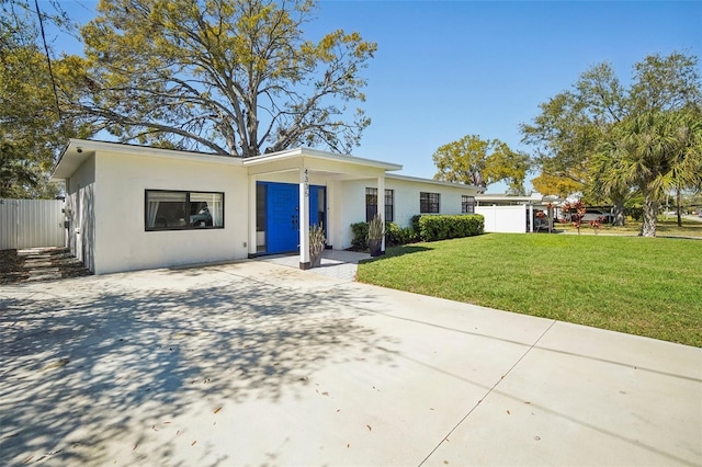 view of front of property with stucco siding, fence, concrete driveway, and a front yard