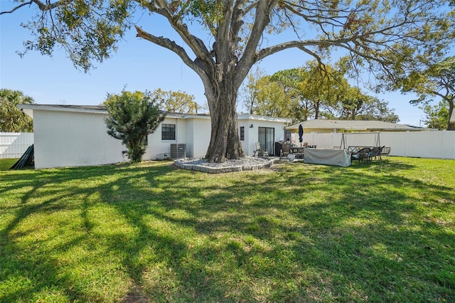 rear view of house with a fenced backyard, a yard, and central air condition unit