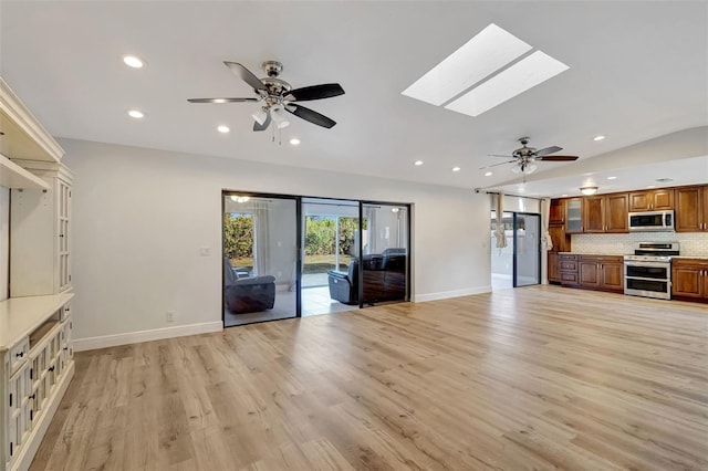 2502 SW 23rd Cranbrook Dr, Boynton Beach, FL 33436 - unfurnished living room featuring vaulted ceiling with skylight, ceiling fan, light wood-type flooring, recessed lighting, and baseboards