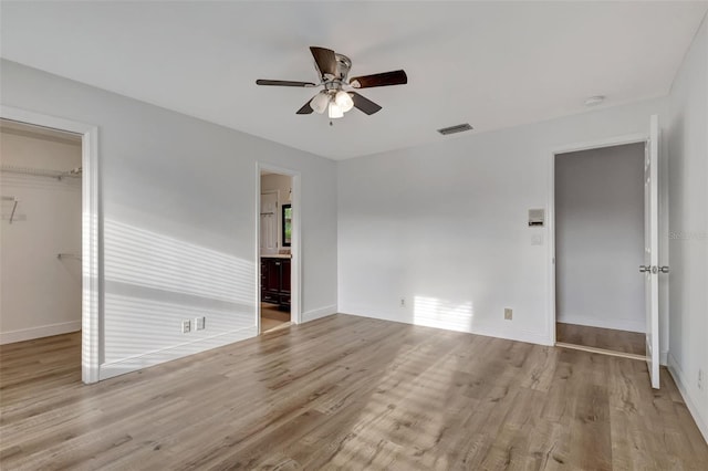2502 SW 23rd Cranbrook Dr, Boynton Beach, FL 33436 - unfurnished bedroom with a walk in closet, wood finished floors, baseboards, and visible vents